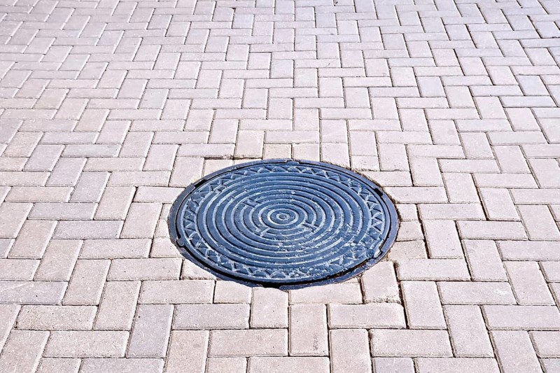 The road of brown tiles with a round metal hatch