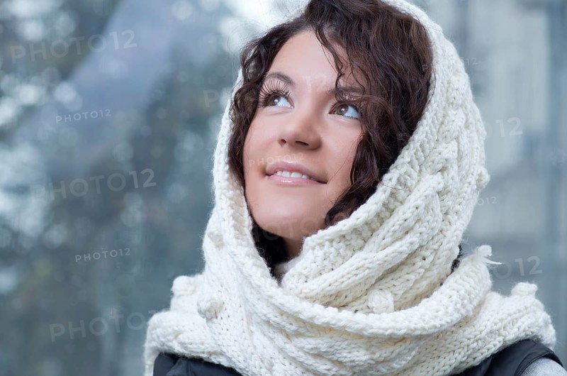 Pretty young caucasian brunette woman wearing white scarf with hood in a outdoor winter portrait