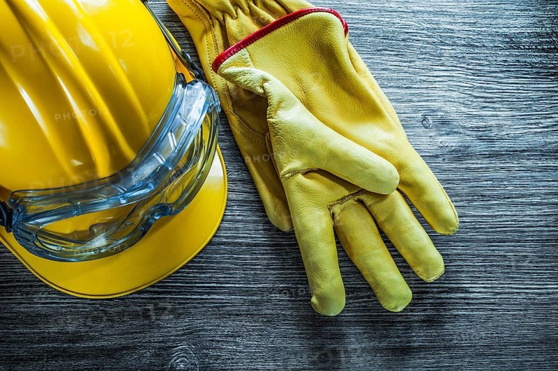 Safety gloves hard hat goggles on vintage wooden board
