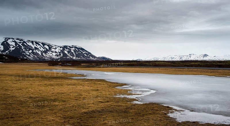 Typical Icelandic dramatic landscape with frozen lake and mountains covered in snow in Iceland