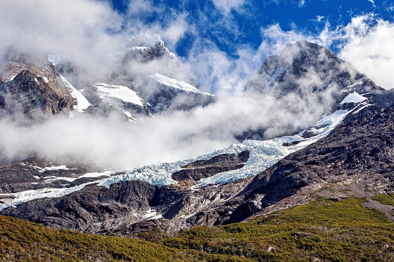 Impressive snow-covered peaks under a clear sky, framed by dramatic clouds, the glaciers of the Torres del Paine National Park in Patagonia, Chile, South America
