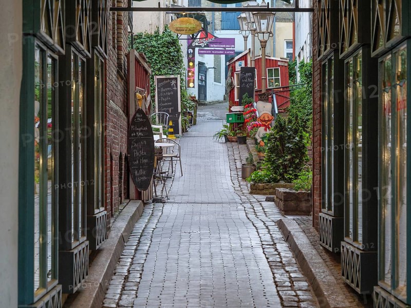 Narrow cobbled alley with old buildings and alleyway café in a cosy atmosphere, Flensburg, Schleswig-Holstein, Germany, Europe