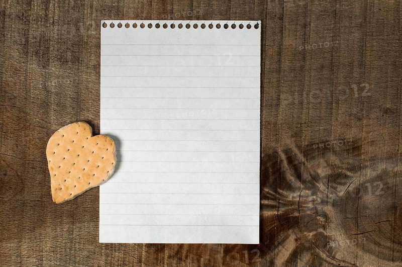 Heart shape cookie on wooden background and white paper sheet