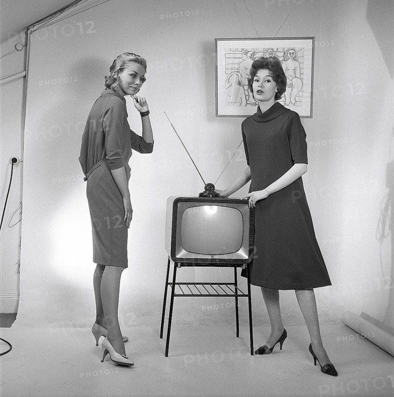 Television in the 1950s. Two young women are standing dressed in a typical 50s dress beside a televison set with an table antenna on top of it. In 1952 1.4 million households in Britain had a television. Photo Kristoffersson ref BZ26. Sweden 1952