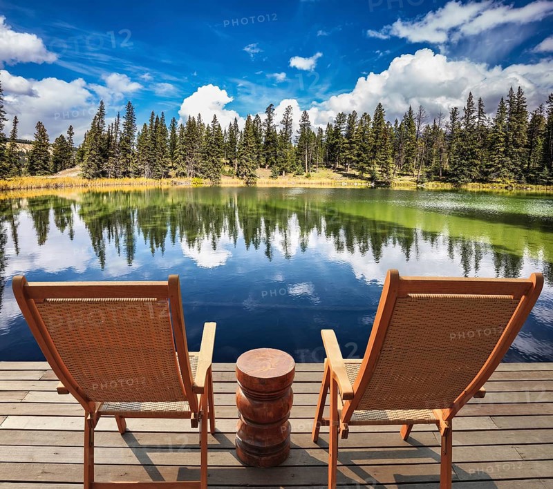 Two wooden deckchairs for tourists on ashore shallow round lake. Autumn day in Jasper National Park in the Rocky Mountains of Canada