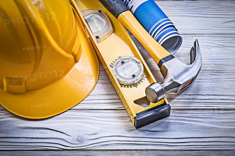 Claw hammer building helmet blue rolled engineering drawings construction level on wooden board