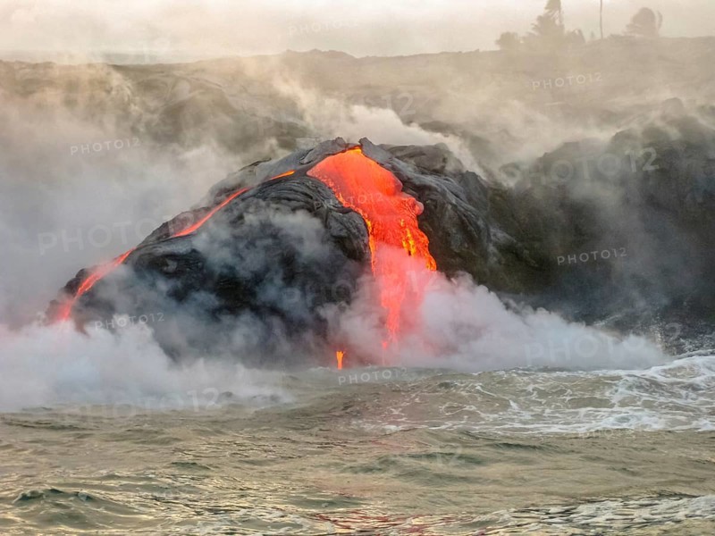Sea view of Kilauea Volcano in Big Island, Hawaii, United States. Shot taken at sunset when the lava glows in the dark as jumps into the sea. The Kilauea erupting since 1983