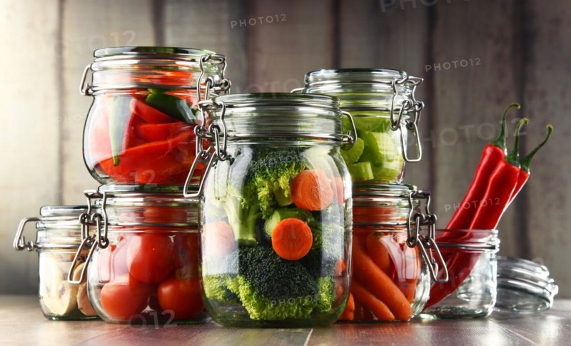 Jars with marinated food and organic raw vegetables