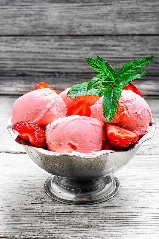 Ice cream with strawberries and leaves of mint in the iron bowl