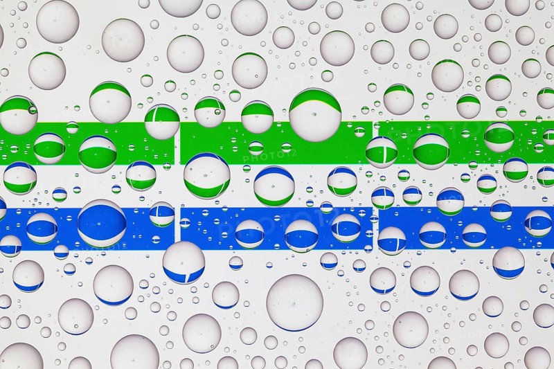 Flags of Sierra Leone behind a glass covered with raindrops. 3D illustration