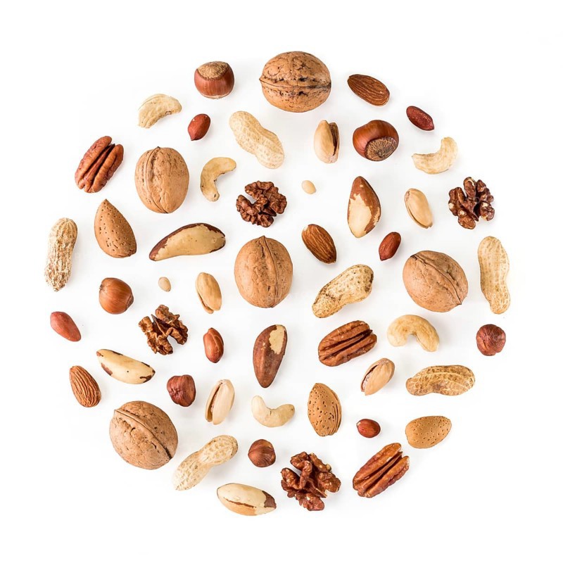 Pattern of nuts in circle form. Various nuts isolated on white. pecan, macadamia, brazil nut, walnut, almonds, hazelnuts, pistachios, cashews, peanuts, pine nuts. Top view or flat-lay. Copy space