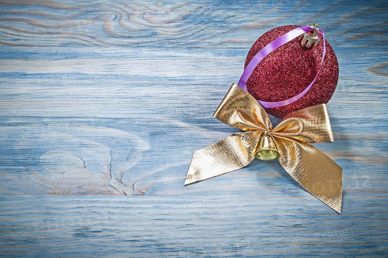 Red Christmas ball golden bow on wooden board holidays concept