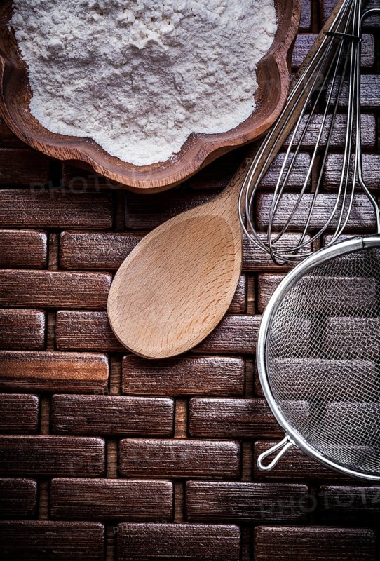 Close up view of wooden spoon bowl flower sieve egg-whisk