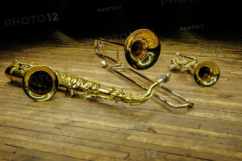 Yellow brass and wind instruments - saxophone, trombone, trumpet on stage with backlight