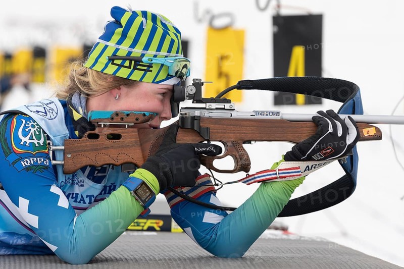 Sportswoman biathlete Anastasia Legostaeva rifle shooting in prone position. Biathlete in shooting range. Open regional youth biathlon competitions East Cup. Kamchatka, Russian Far East, Apr 12, 2019