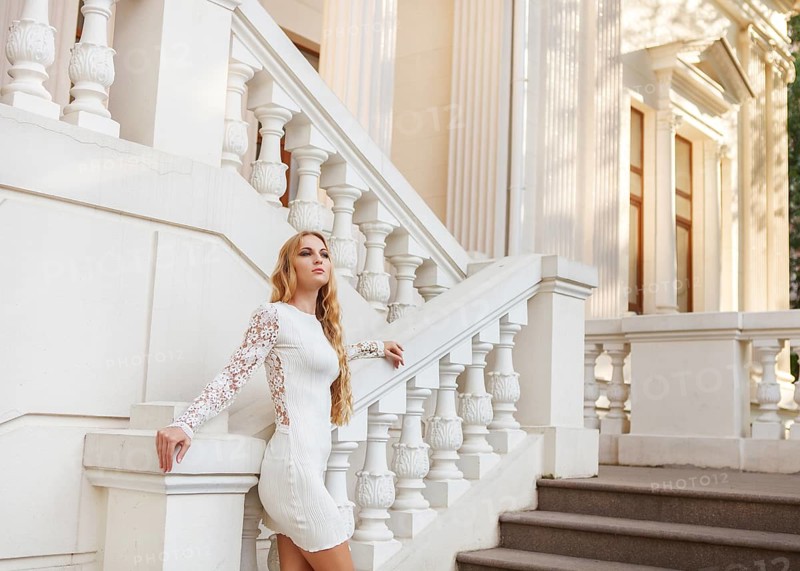 Beautiful blond woman in white dress outdoors on the stairs
