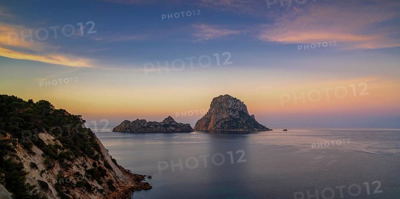 A panorama landscape view of the landmark Es Vedra island and rocks off the coast of Ibiza at sunrise