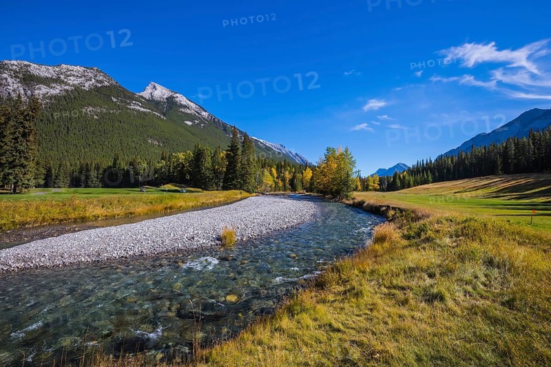 Magnificent valley in Banff National Park. Beneaped autumn stream with a pebbly bottom flows among the mountains and pine forests