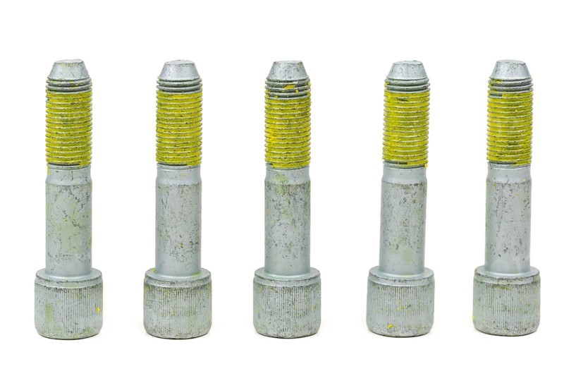 Five bolts for the car with the yellow glue on the threads. Isolate on white