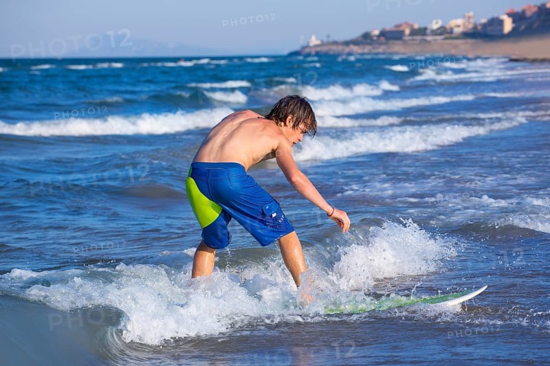 Boy surfer surfing waves on the beach enjoying fun