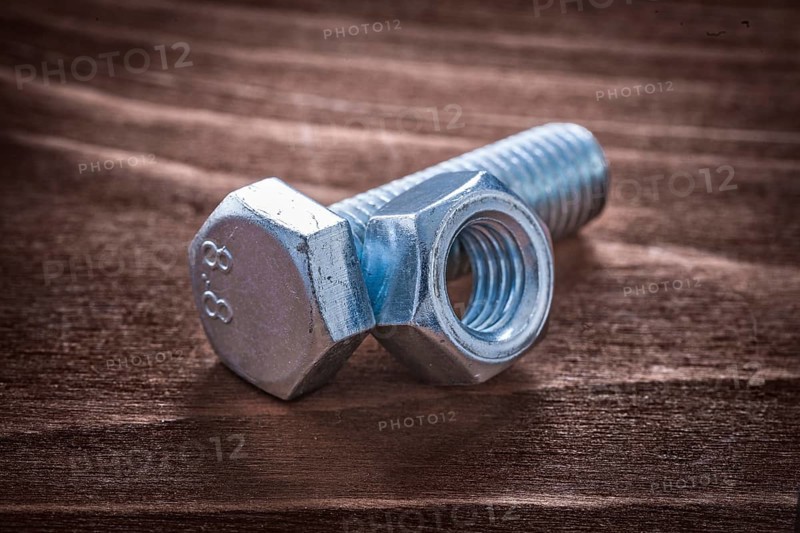 Threaded metal bolt and screw nut on vintage wooden board repairing concept