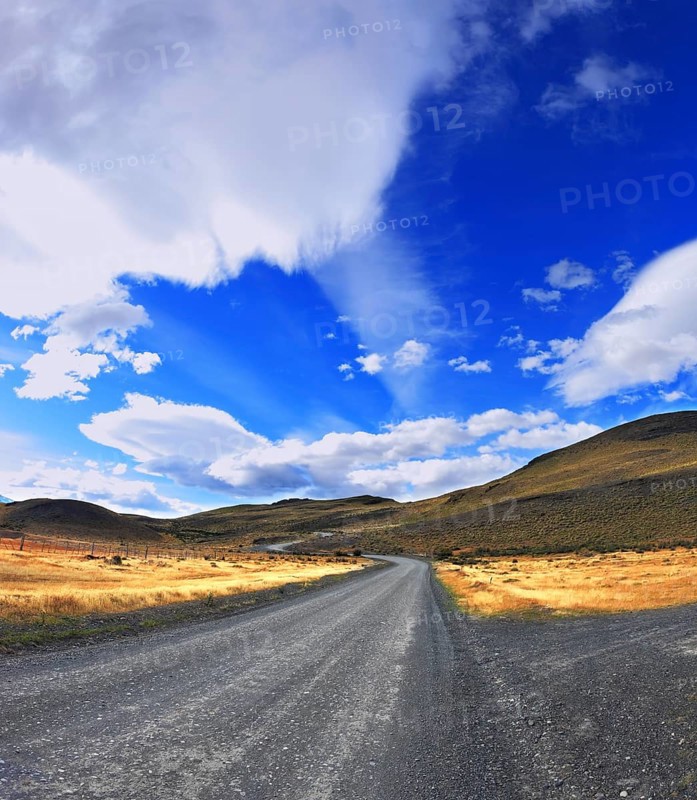 Picture taken with a fisheye lens. The dirt road in the Chile National Park Torres del Paine. Magic clouds incredible shapes formed by glaciers shining in the sun. Patagonia