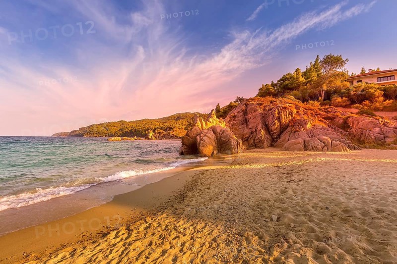 Vourvourou, Chalkidiki or Halkidiki, Greece summer sunset scenery with turquoise sea, forest green mountains and rocks at Fava sandy beach
