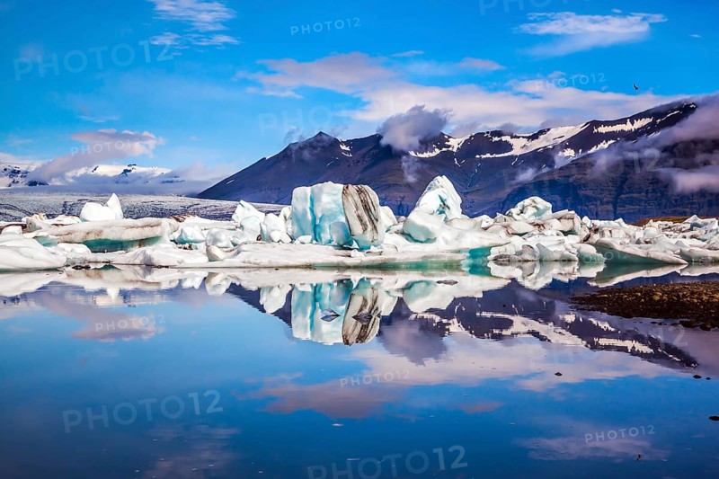 Icebergs and ice floes are reflected in the smooth water surface. Drift ice Ice Lagoon - Jokulsarlon. Morning in the Iceland. The concept of extreme northern tourism