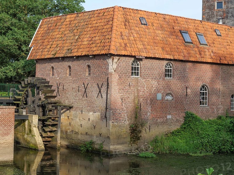 Detailed view of a brick watermill with water wheel and surrounding vegetation, winterswijk, gelderland, the netherlands