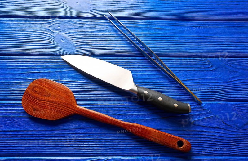 Chef tools knife tweezers and spatula on a blue wooden background