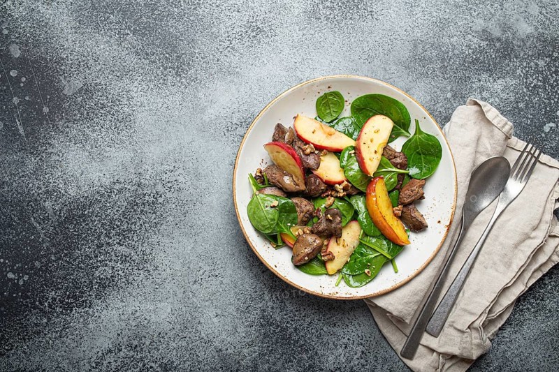 Healthy Salad with Iron Rich Ingredients Chicken Liver, Apples, Fresh Spinach and Walnuts on White Ceramic Plate, Grey Rustic Stone Background Top View Copy Space, food photography, food photography