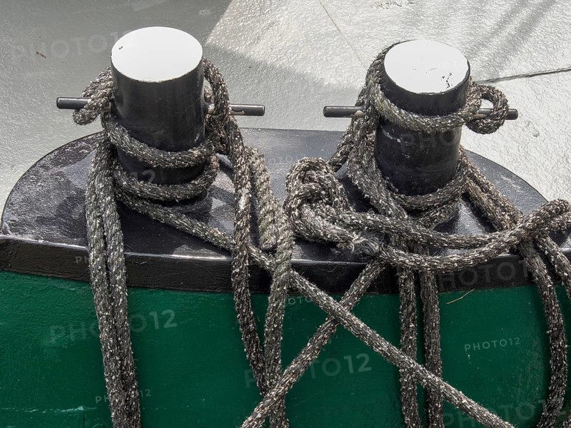 Close-up of two black metal bollards on a boat, surrounded by ropes and knots, carolinensiel, germany