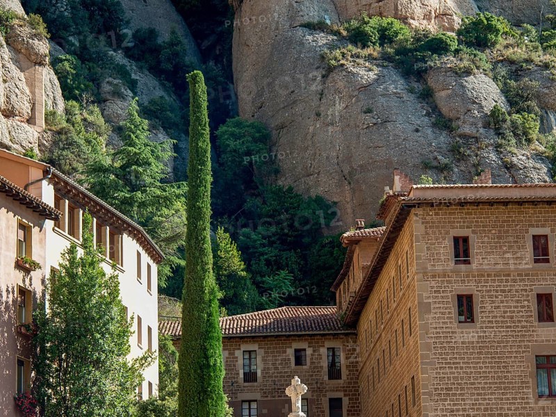 Stone building built against the rocks, surrounded by trees and vegetation, montserrat, spain
