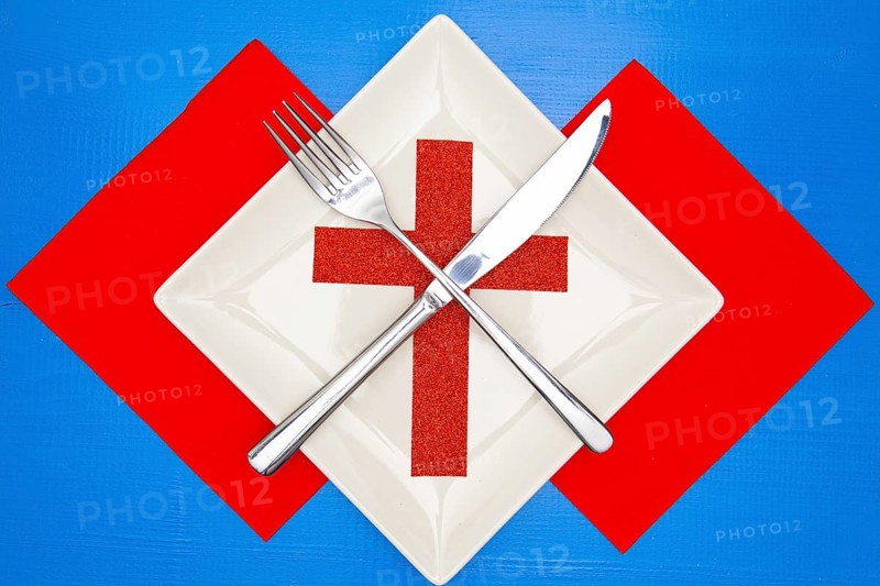 White square plate and red Christmas decoration on the blue wooden table.Top view.Flat Lay Image