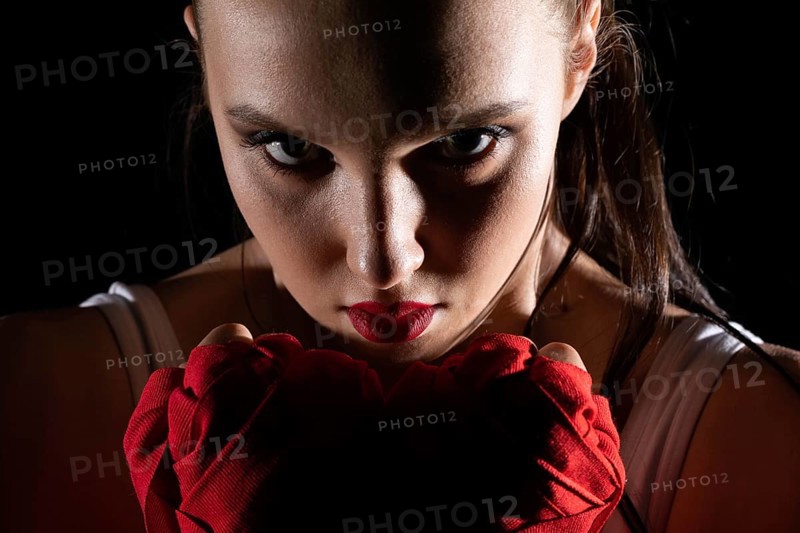 The head is hidden behind the strong guard of a professional sportswoman. A strong and athletic woman in the ring of sports which is MMA