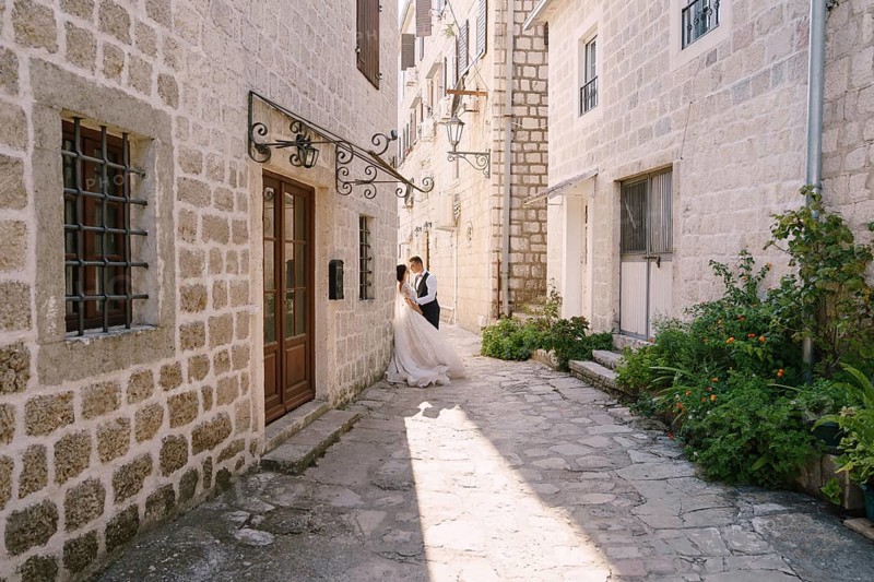 Wedding couple on the street of the old city, among ancient houses. Fine-art wedding photo in Montenegro, Perast