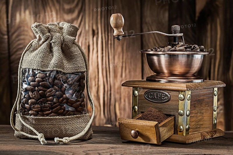 Vintage sack with coffee beans and wooden mill on wood background