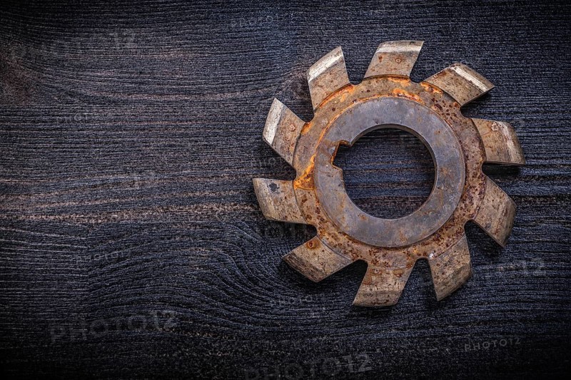Vintage rotary cutter with cogs on wood board construction concept