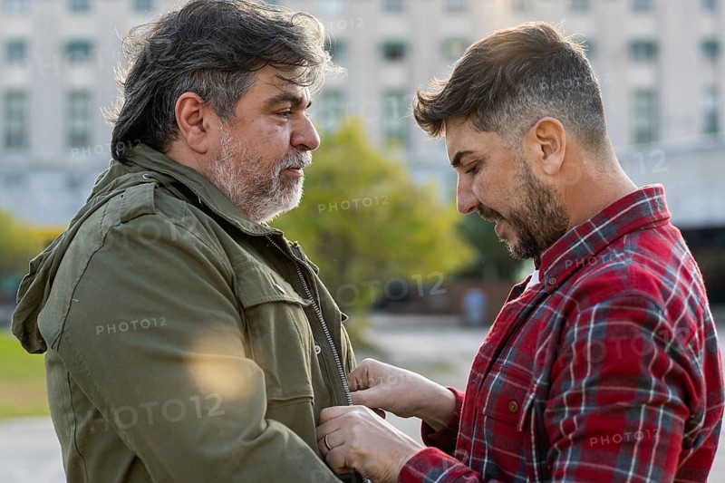 A man is adjusting his husband's jacket