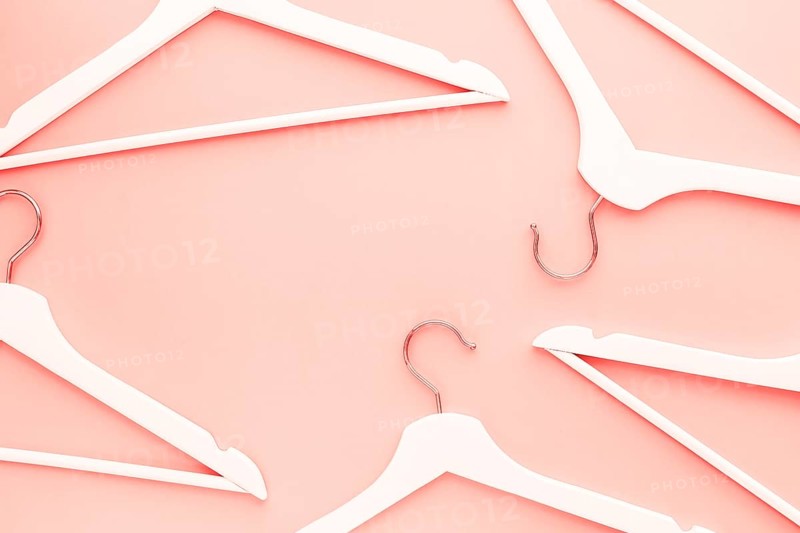 Creative top view flat lay wooden hangers toned living coral color of the year 2019 background copy space minimalism style. Template fashion blog social media sale store promo design shopping concept