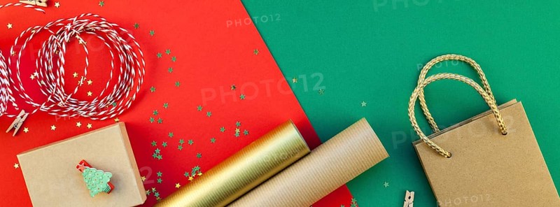 New Year or Christmas presents preparation DIY flat lay top view Xmas holiday celebration handmade gift boxes on red green paper background. Long wide banner greeting card or your text design 2019