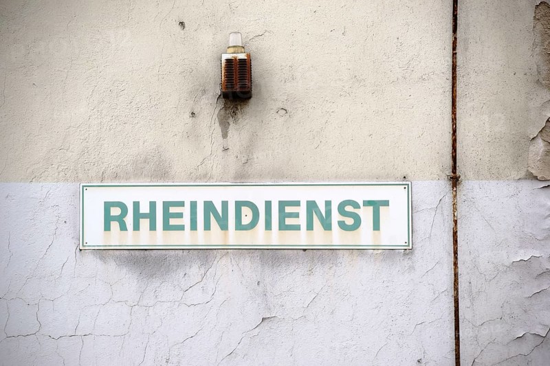 A close-up of a warning light with a rusty siren and a sign on the wall of an industrial ruin
