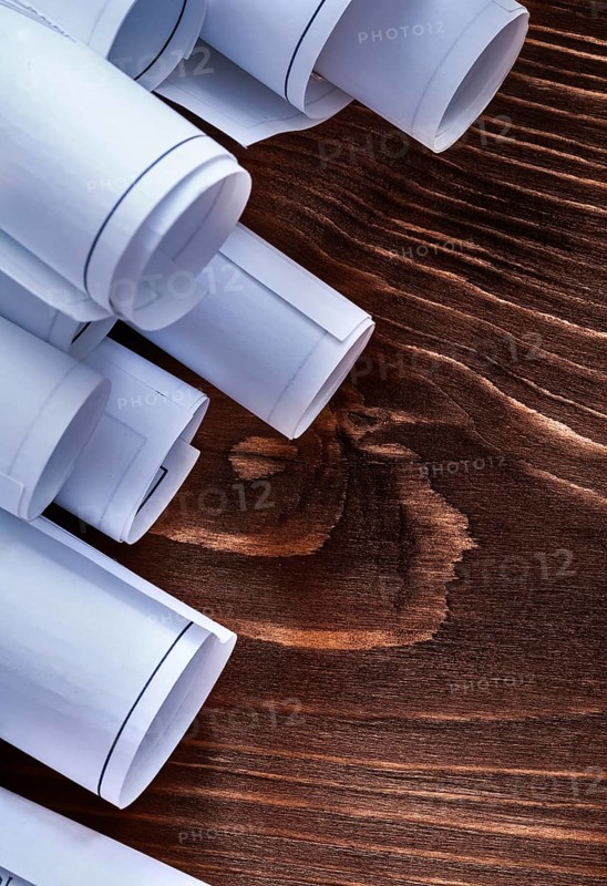 Rolls of construction plans on vintage wooden pine board maintenance concept
