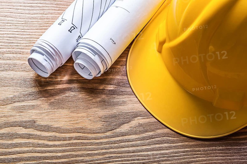 Rolled engineering drawings hard hat on wooden board construction concept