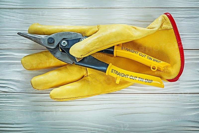 Protective gloves tin snip on wooden board