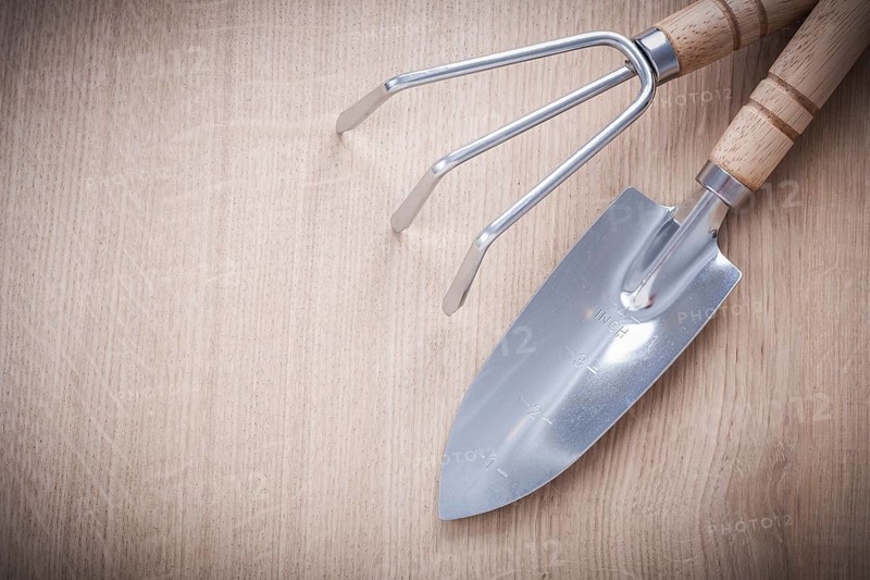 Stainless gardening trowel fork with sharp hand spade on wooden board horizontal version agriculture concept