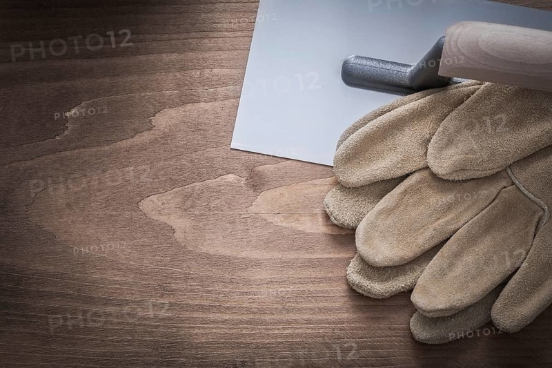 Protective gloves and plastering trowel construction concept