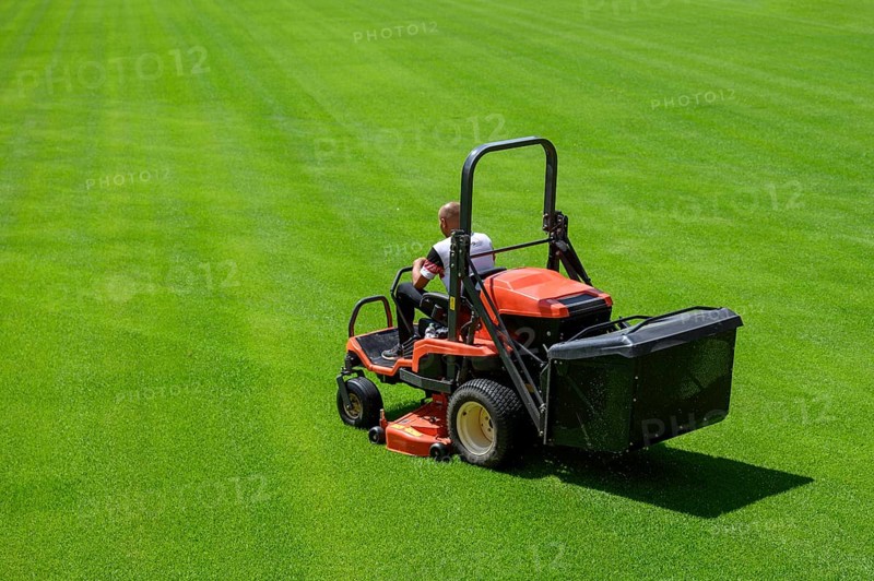 Mowing grass at the football stadium in Lubin, Poland, Europe