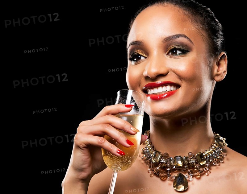 Romantic Indian woman with golden makeup and nailpolish. Big gold fashion necklace. Black isolated background. Holding glass of champagne, Toronto, Canada, North America