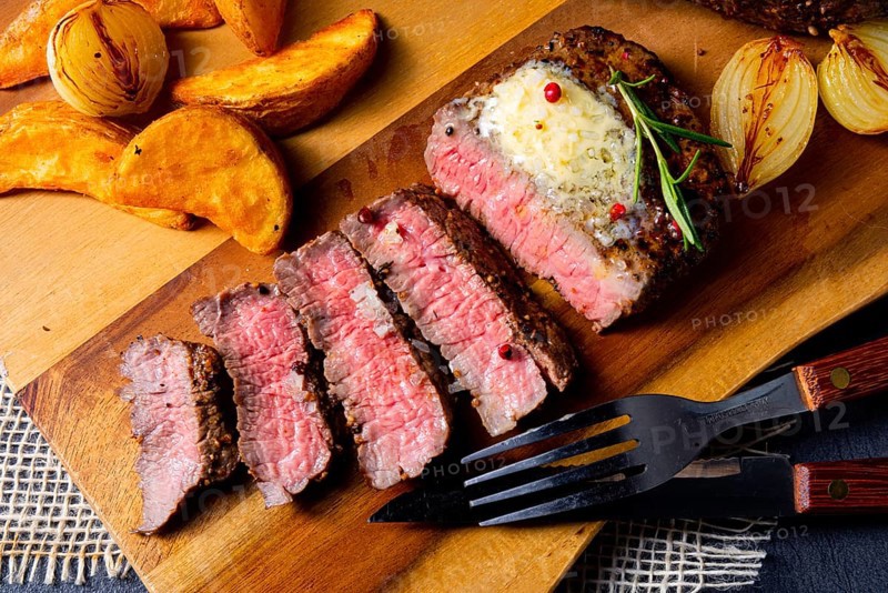 Rustic medium rare beef steak with herbs and potato wedges
